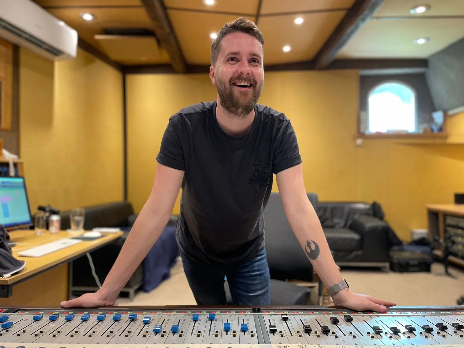 Elliot smiling, leaning on a mixing desk in the studio